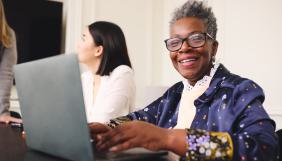 Femme souriante tapant sur son clavier d'ordinateur