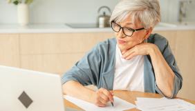 Femme senior écrivant devant un ordinateur